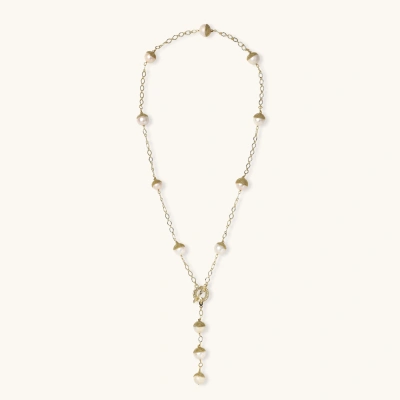 Gold-plated lariat necklace with baroque pearls and textured caps on cream background, showing adjustable Y-shaped design.