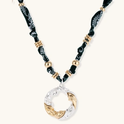 Adjustable necklace with black paisley fabric cord, gold metal spacers, and clear twisted pendant on cream background