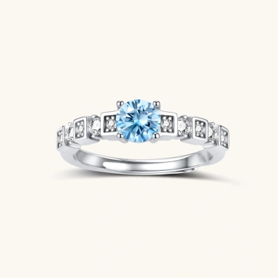 Geometric sterling silver ring with light blue moissanite center stone and square diamond accents on white background