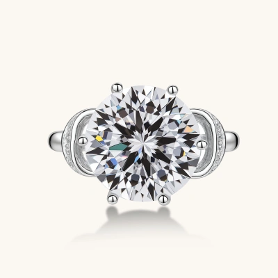 Sterling silver ring with 5ct round moissanite center stone and intricate bow design with pavé accents on white background.