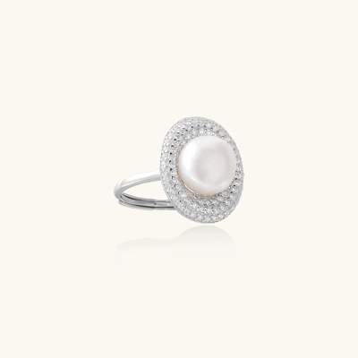 Silver ring with lustrous white pearl center surrounded by sparkling crystal halo on light background.
