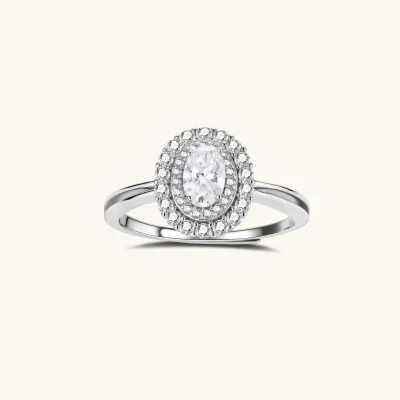Sterling silver ring with oval moissanite center stone surrounded by double halo of sparkling stones on neutral background.