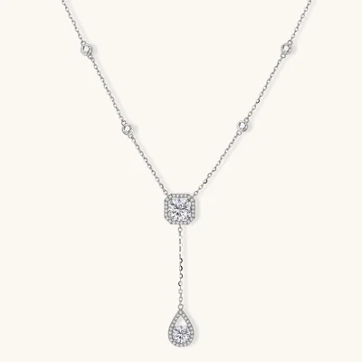 Sterling silver necklace with cushion-cut moissanite in halo setting and teardrop pendant, displayed on cream background.