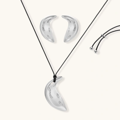 Crescent moon shaped pendant and earrings in eco-zinc alloy with curved crystal inlay patterns on light background.