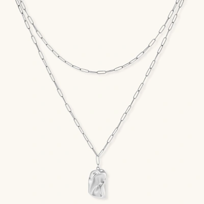 Silver layered necklace with organic flowing pendant in eco-zinc alloy on neutral background, showing adjustable chain design.