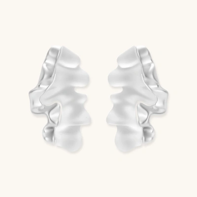 Pair of silver-toned sculptural earrings with flowing abstract forms and stud backs against white background.