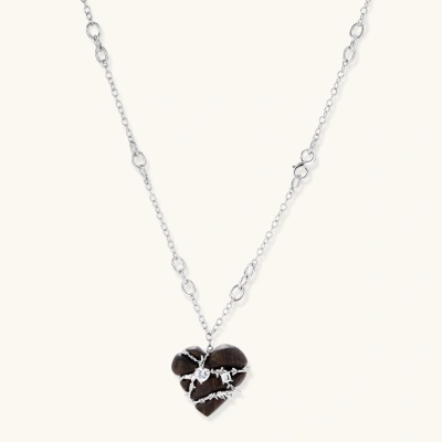 Dark ebony wood heart pendant wrapped with brass wire and zirconia crystals on adjustable chain against cream background
