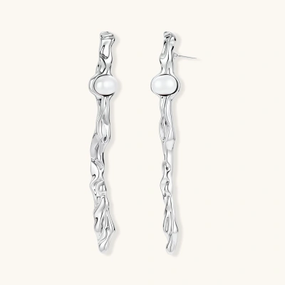 Sculptural silver drop earrings with flowing twisted design and white pearls on neutral background.