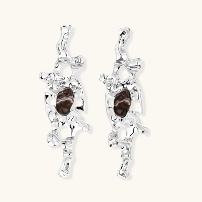 Flowing silver-toned earrings with organic liquid shapes and embedded brown resin stones on white background.