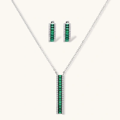 White gold plated jewelry set with emerald green rectangular stones and clear crystals in geometric rows on white background.
