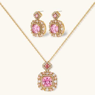Ornate gold-plated jewelry set with rose pink zirconia center stones and crystal accents on cream background.