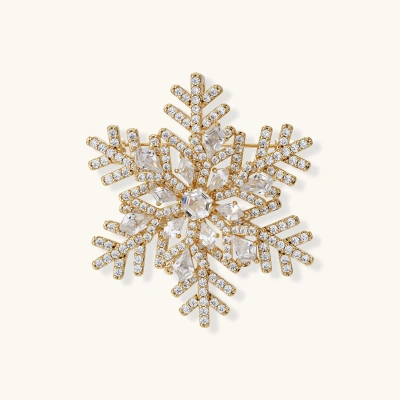 Ornate gold-plated snowflake brooch with geometric crystal pattern and sparkling zirconia stones on cream background.