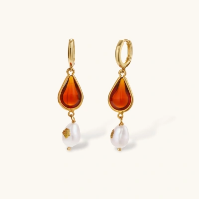Gold-plated drop earrings featuring amber teardrops and white baroque pearls on light background.