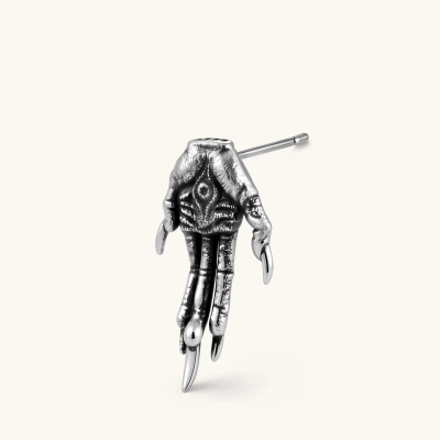 Silver stainless steel stud earring shaped like a skeletal demon claw hand with an eye motif on the palm and sharp talon fingers.