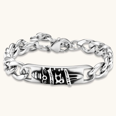 Silver 316L stainless steel Cuban chain bracelet with blackened skull and crown ID bar centerpiece, lobster clasp closure.