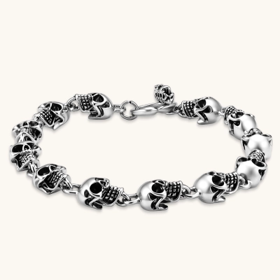 Silver stainless steel bracelet with linked 3D skull charms and a spring-ring clasp, oxidized black detailing, 225mm length.