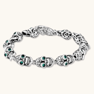 Silver stainless steel skull link bracelet with green crystal eye sockets and engraved detailing, toggle clasp closure.