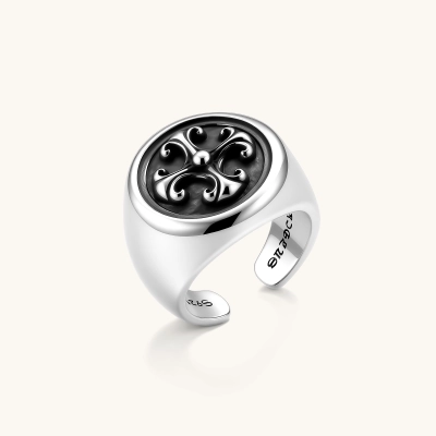 925 sterling silver open signet ring with dark oxidized fleur-de-lis cross motif on circular face, adjustable cuff band.