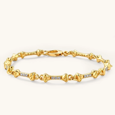 Gold-plated sterling silver bracelet with bone-shaped links, embedded CZ stones, and lobster clasp on light background.