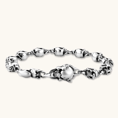 Sterling silver bracelet with linked skull motifs, decorative scroll engravings, and a large skull lobster-claw clasp.