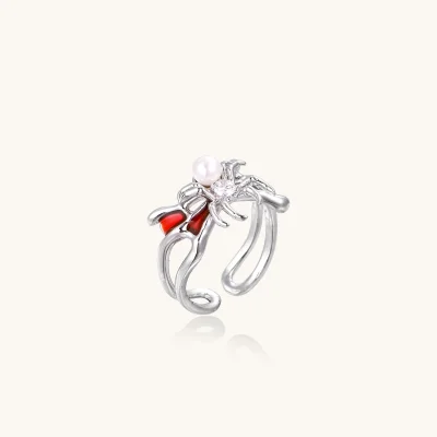 Silver-tone spider ring with red drip wings, a white bead and a round zirconia center on an open adjustable band.