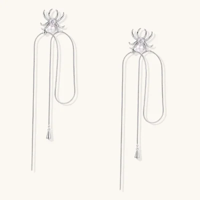 Pair of silver-tone spider earrings with a zirconia center, a white bead body and long snake chain tassels with teardrop ends.