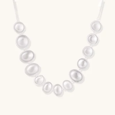 Sterling silver necklace with fourteen matte concave round and oval discs on a curb chain with an adjustable extender.