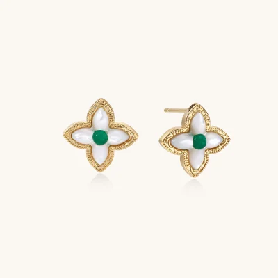 Pair of four-petal stud earrings in 18K gold plated eco-brass with white MOP petals and a round green gemstone center on cream.
