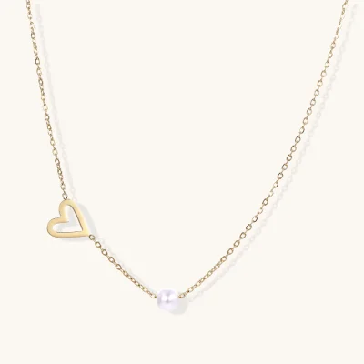 Dainty 14K gold plated stainless steel necklace with an open heart charm and a single round white bead on a cream background.