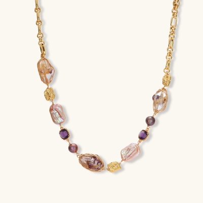 Gold plated chain necklace with wire-wrapped baroque pearls, purple faceted stones and textured gold beads on a cream background.