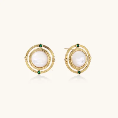 Circular gold stud earrings with iridescent mother-of-pearl center and green zirconia accents on cream background.