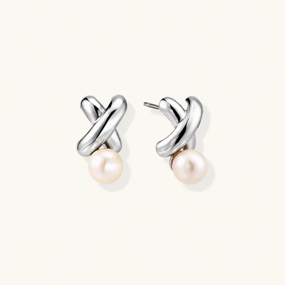 Rhodium-plated silver earrings with twisted X design and freshwater pearl drops on beige background