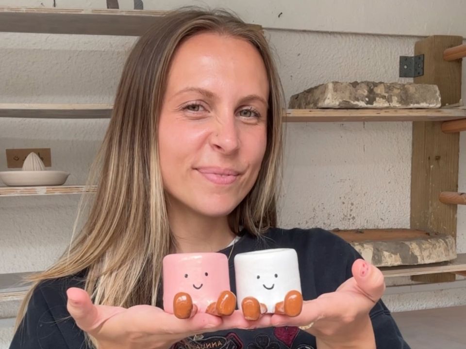 Kit holding two little clay marshmallow pots she made