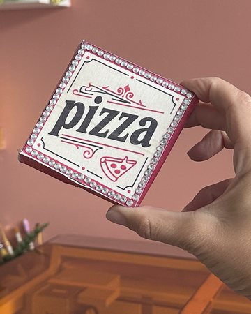 A mini pizza box made on the xTool M2 Color, held up above the machine