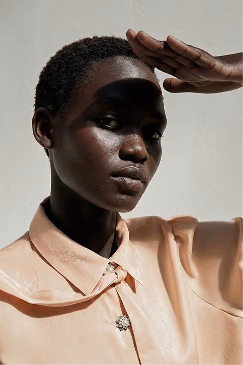 Person wearing beige pants and white Adidas Samba sneakers with red stripes stepping out of a car.