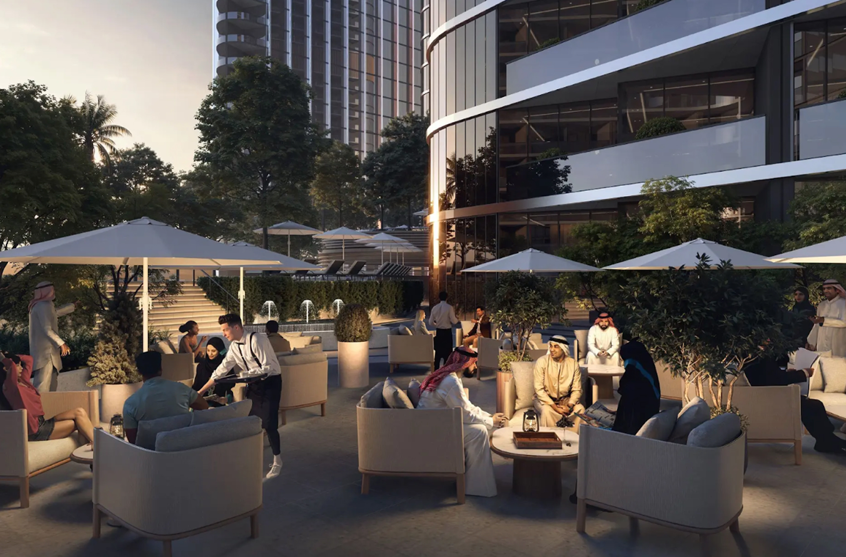 Outdoor lounge area at sunset with people sitting under umbrellas, modern building, and greenery.