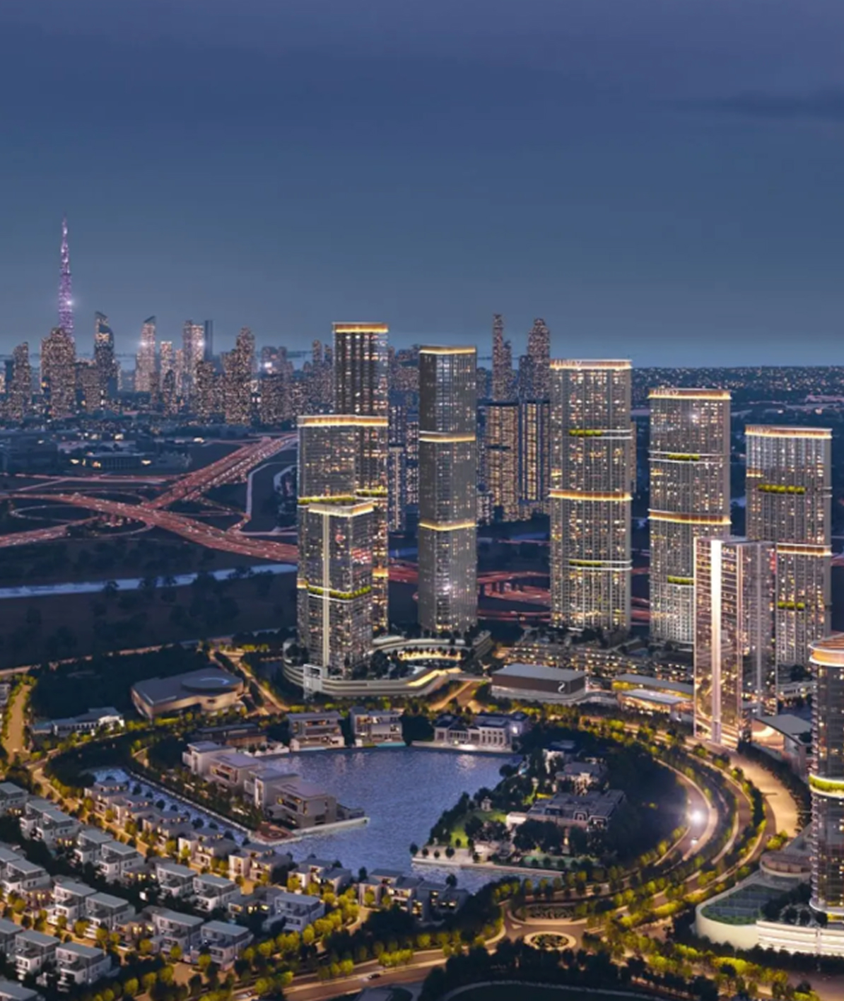 Night aerial view of a modern cityscape with illuminated high-rise buildings surrounding a central water body and highways in the background.