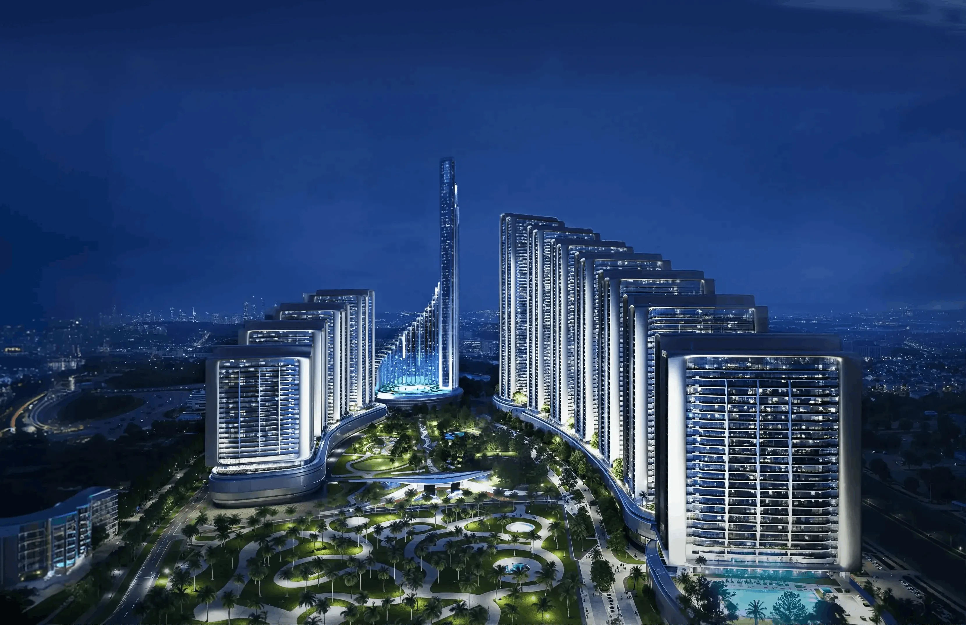 Illuminated modern high-rise buildings surrounding a landscaped park with winding paths and palm trees at night.