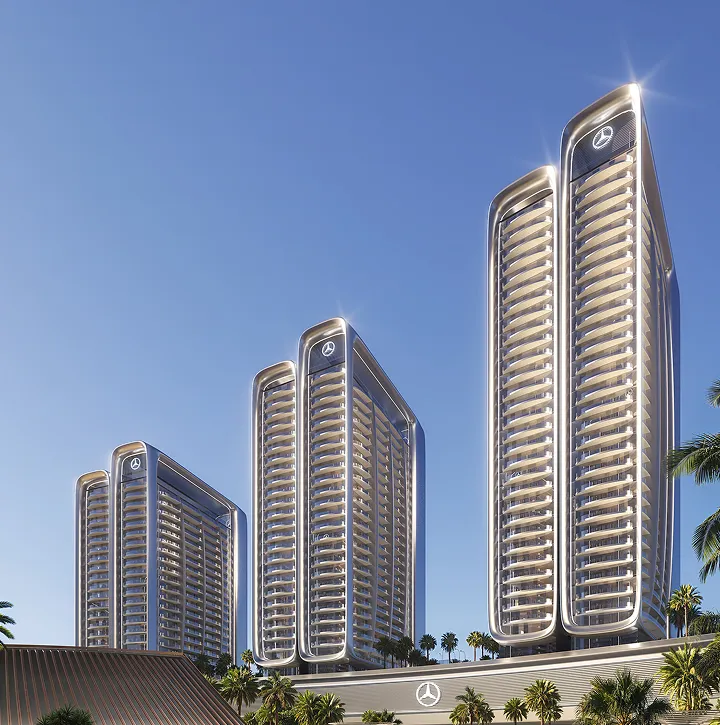 Four modern high-rise buildings with sleek curved designs and illuminated Mercedes-Benz logos at the top and base, set against a clear blue sky and surrounded by palm trees.