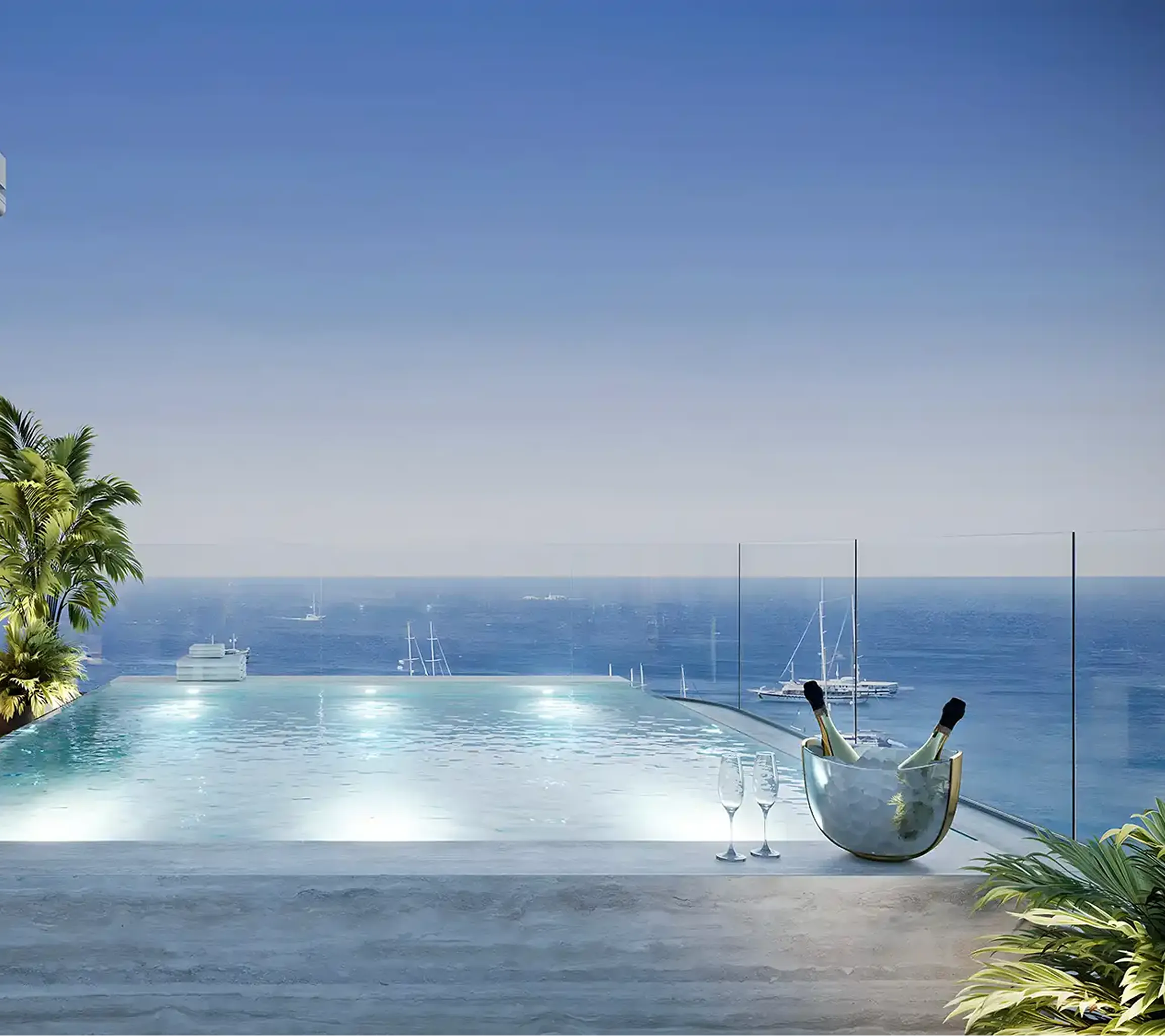 Infinity pool overlooking the ocean with two champagne bottles in an ice bucket and two empty glasses on the edge.