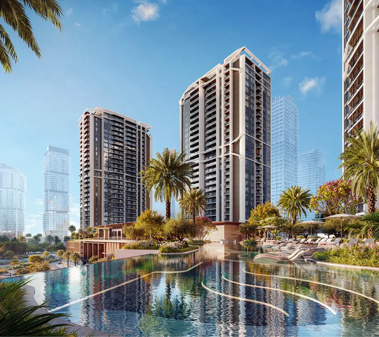 Modern high-rise residential buildings with balconies surrounding a large outdoor swimming pool and palm trees under a clear blue sky.