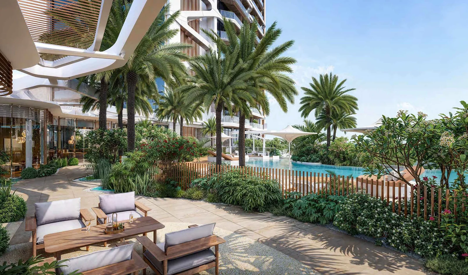 Outdoor seating area with cushioned wooden chairs and a table near a pool surrounded by palm trees and lush greenery.