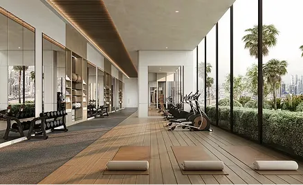 Modern gym with yoga mats, stationary bikes, weights, and large floor-to-ceiling windows overlooking greenery and cityscape.