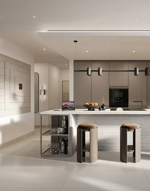 Modern kitchen with a marble island featuring two wooden stools, built-in oven, hanging lights, and a laptop on the counter.