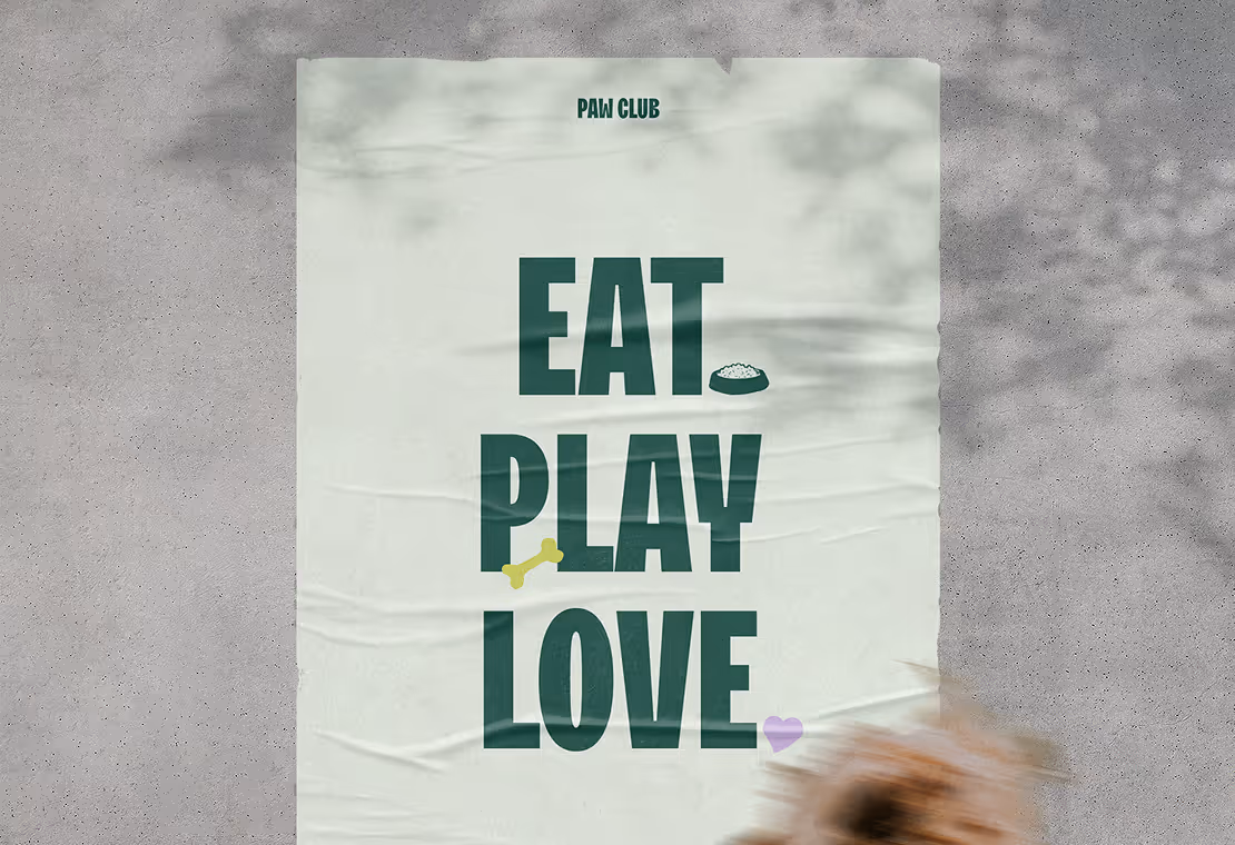 Poster on a concrete wall with text 'PAW CLUB EAT PLAY LOVE' and small icons of a dog bone, food bowl, and heart, with a blurred dog in the foreground.