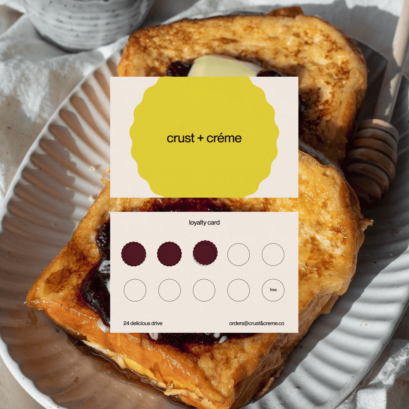 Two slices of French toast on a plate with a honey dipper and a loyalty card with three stamps and text 'crust + crème'.