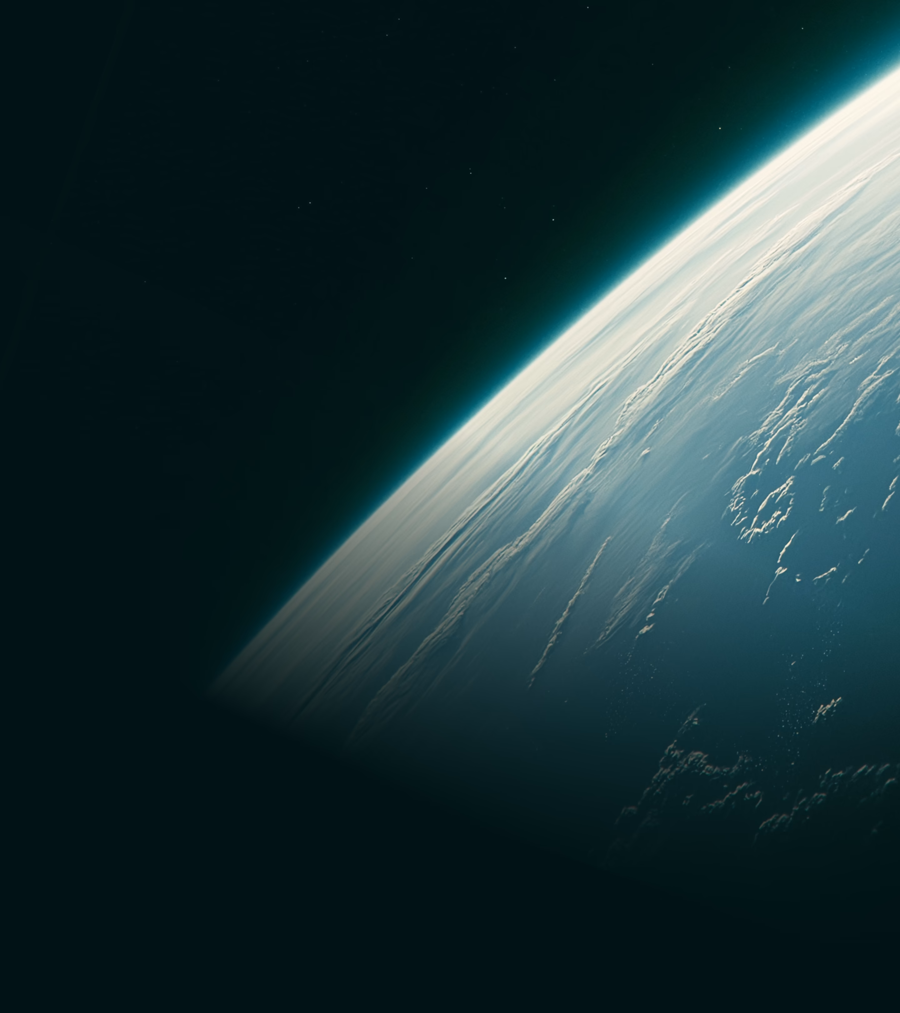 Curved edge of Earth viewed from space showing atmosphere and cloud formations against dark space background.