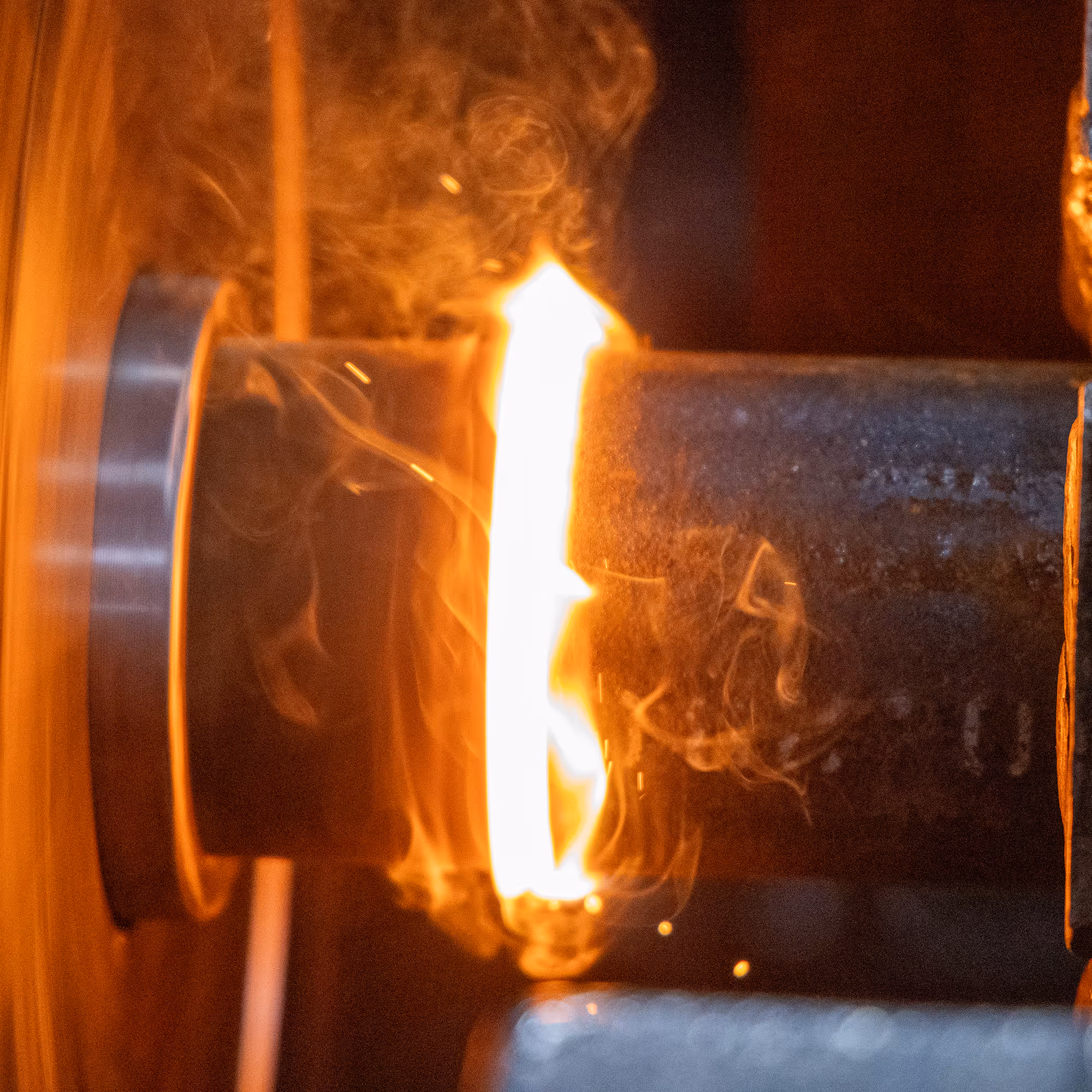 Close-up of a bright orange welding flame between two metal pieces.