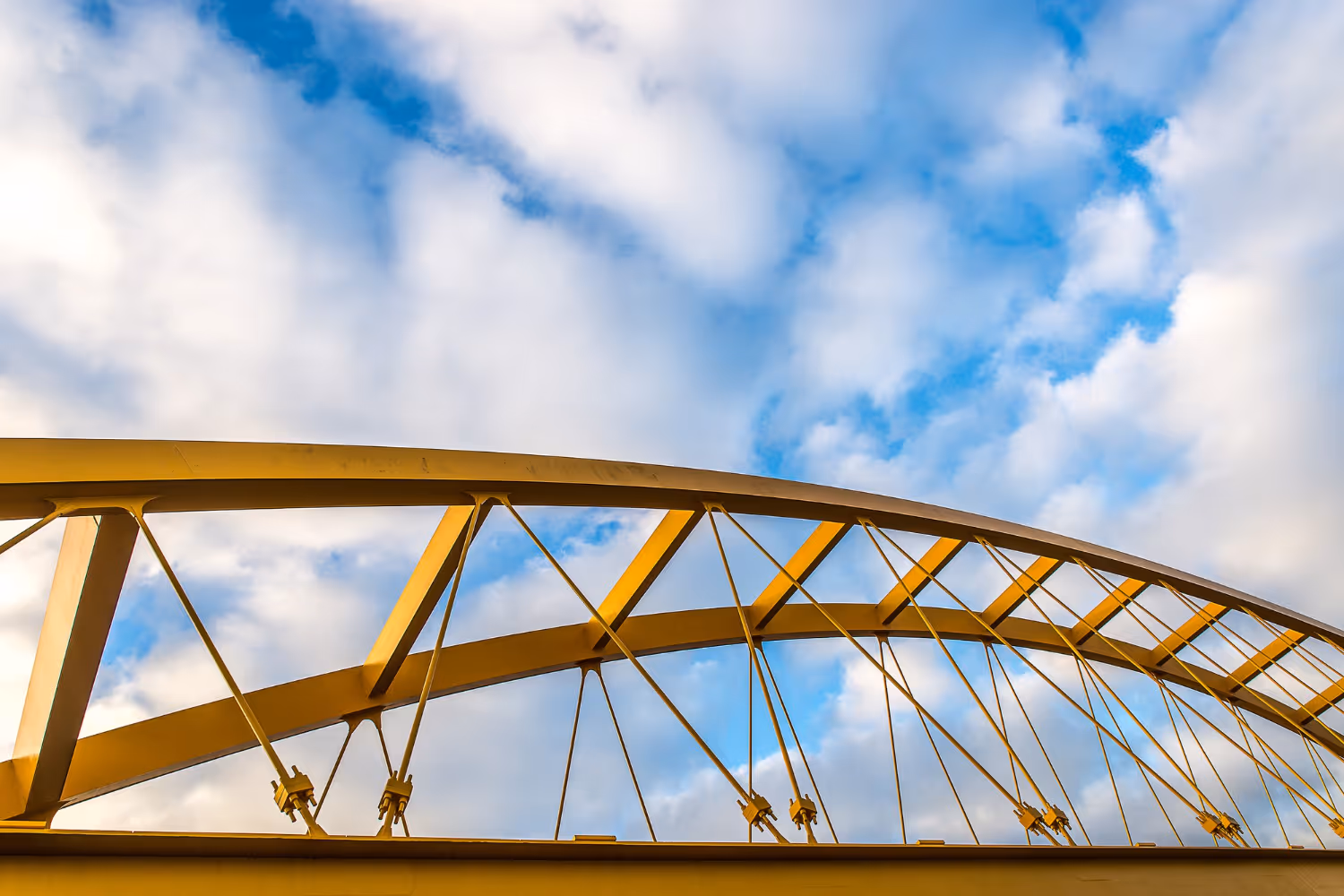 Stacks of metal screw piles with helical plates stored outdoors under a clear blue sky.