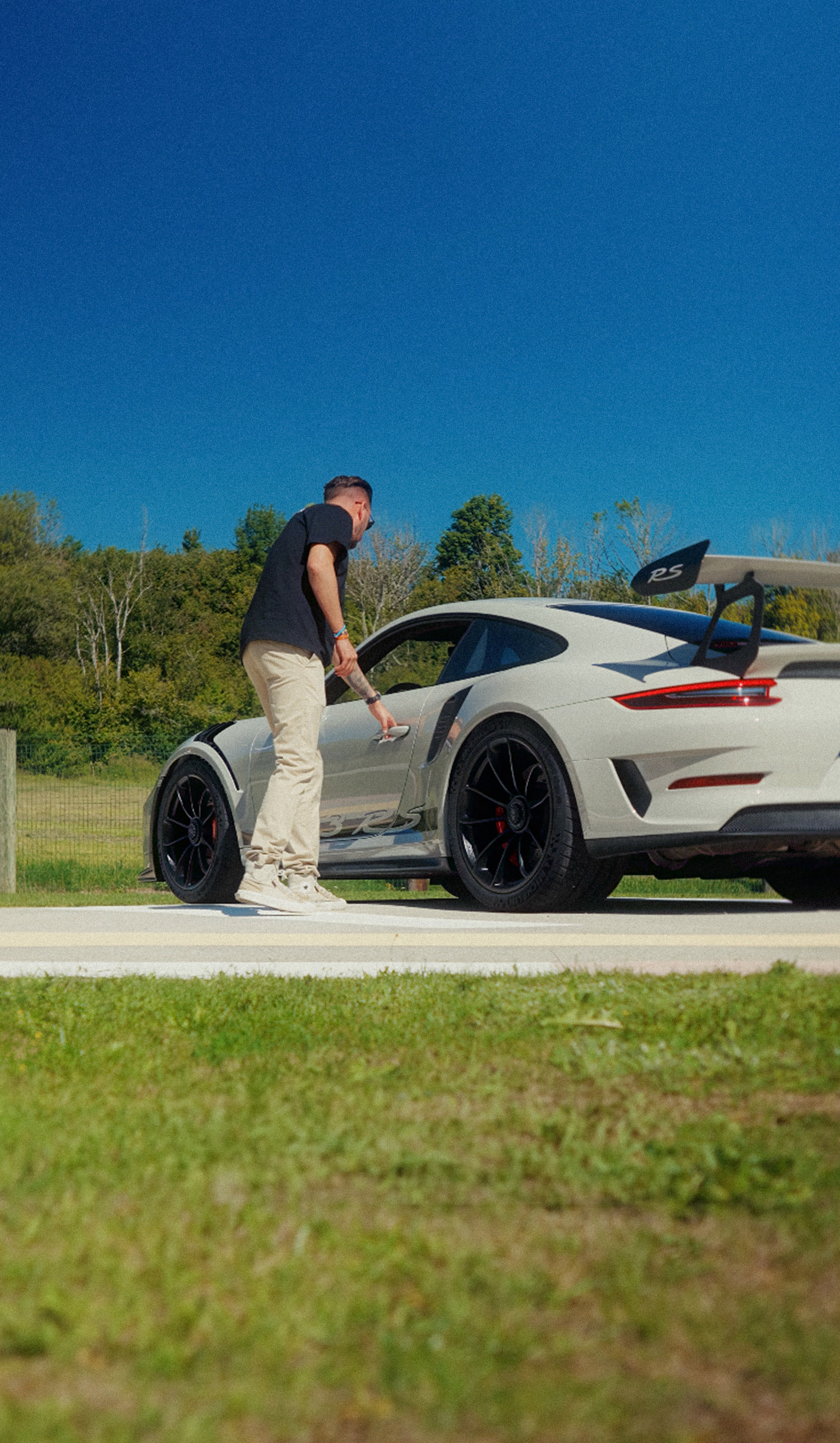 Le propriétaire à côté de sa Porsche 911 GT3 RS blanche, portière ouverte